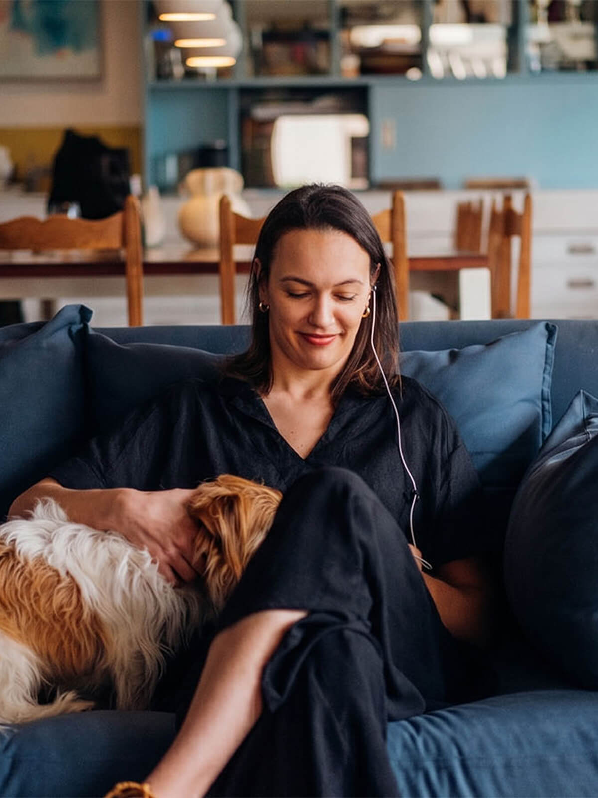 Member relaxing on a sofa with her dog while listening to her coach